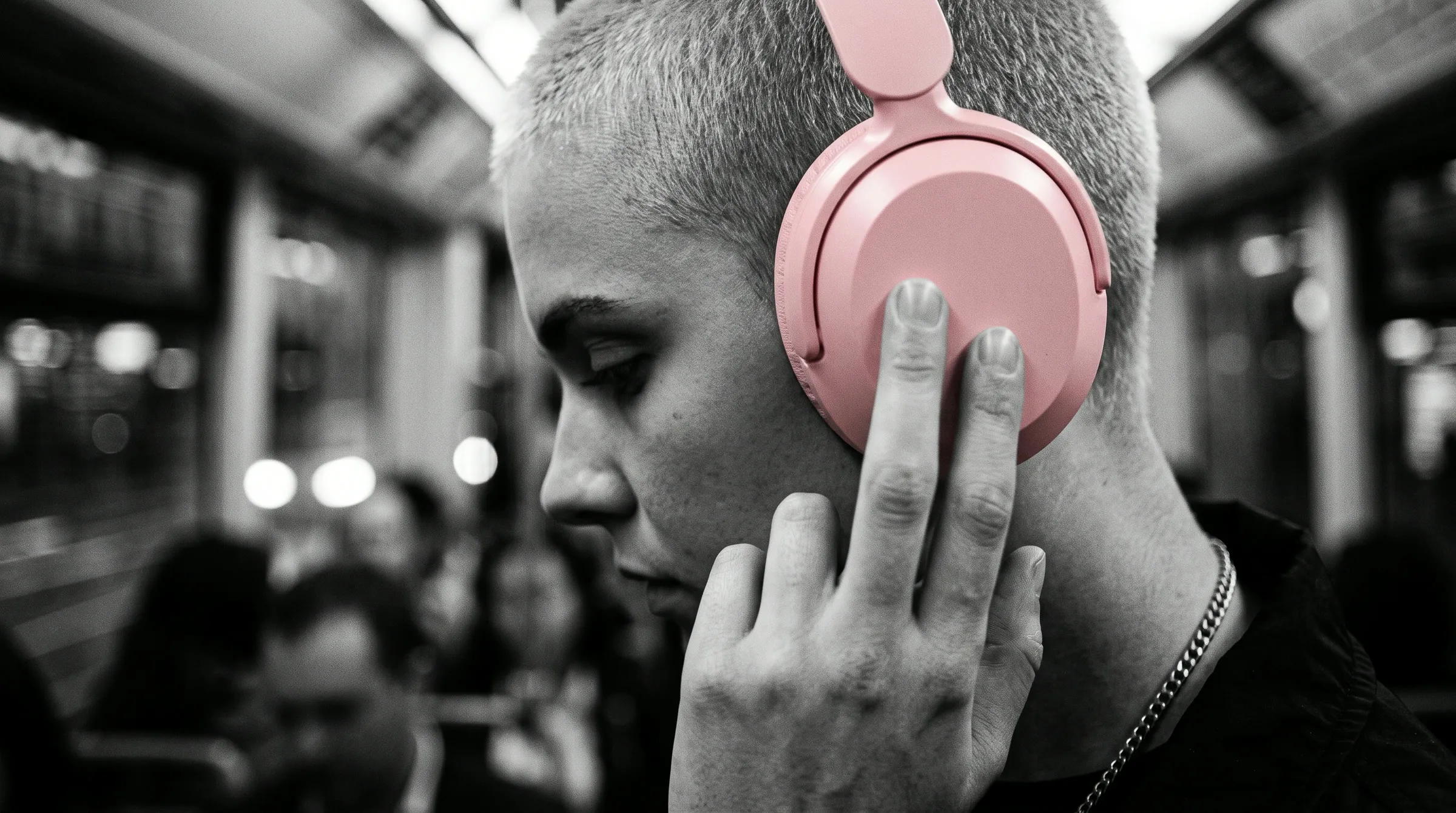 Close-up of a hand pressing the earcup of blush pink Still headphones