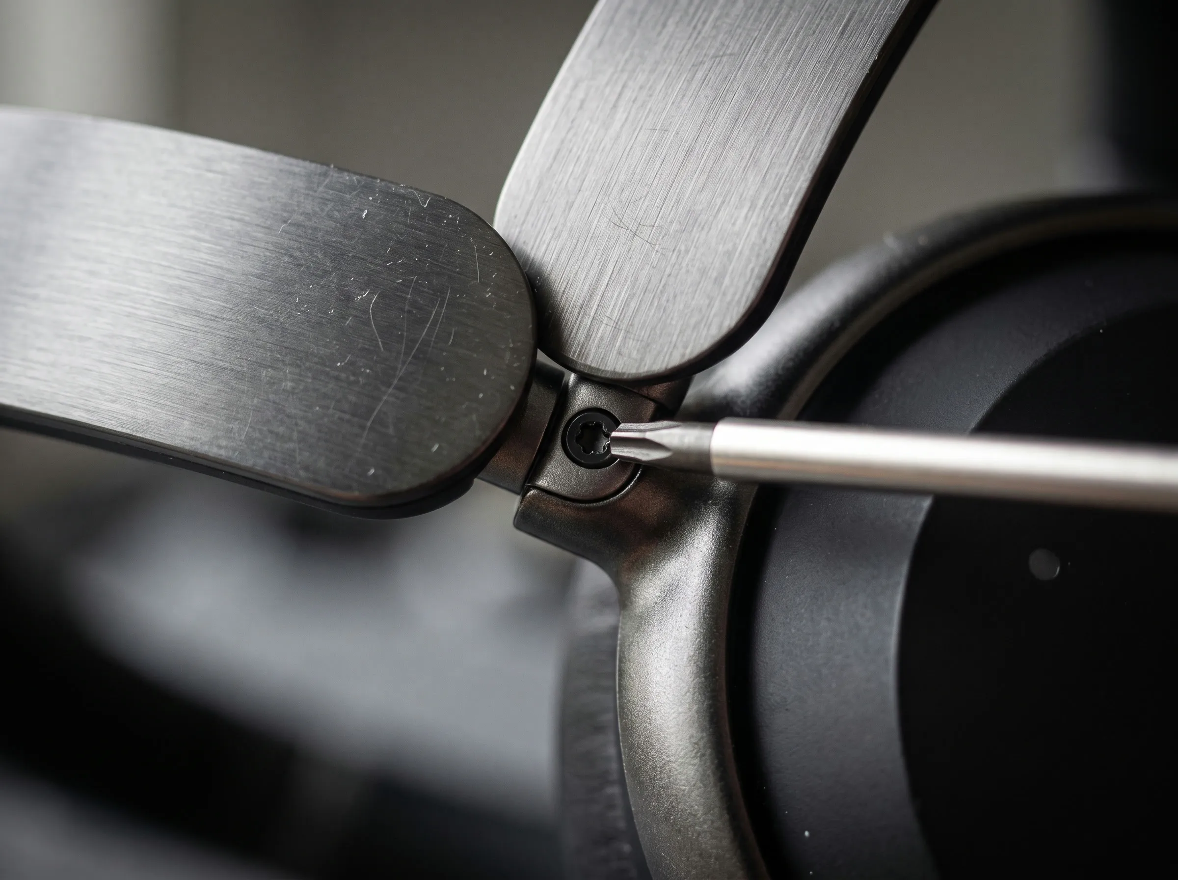 Macro close-up of a screwdriver in the hinge screw of a pair of Still headphones