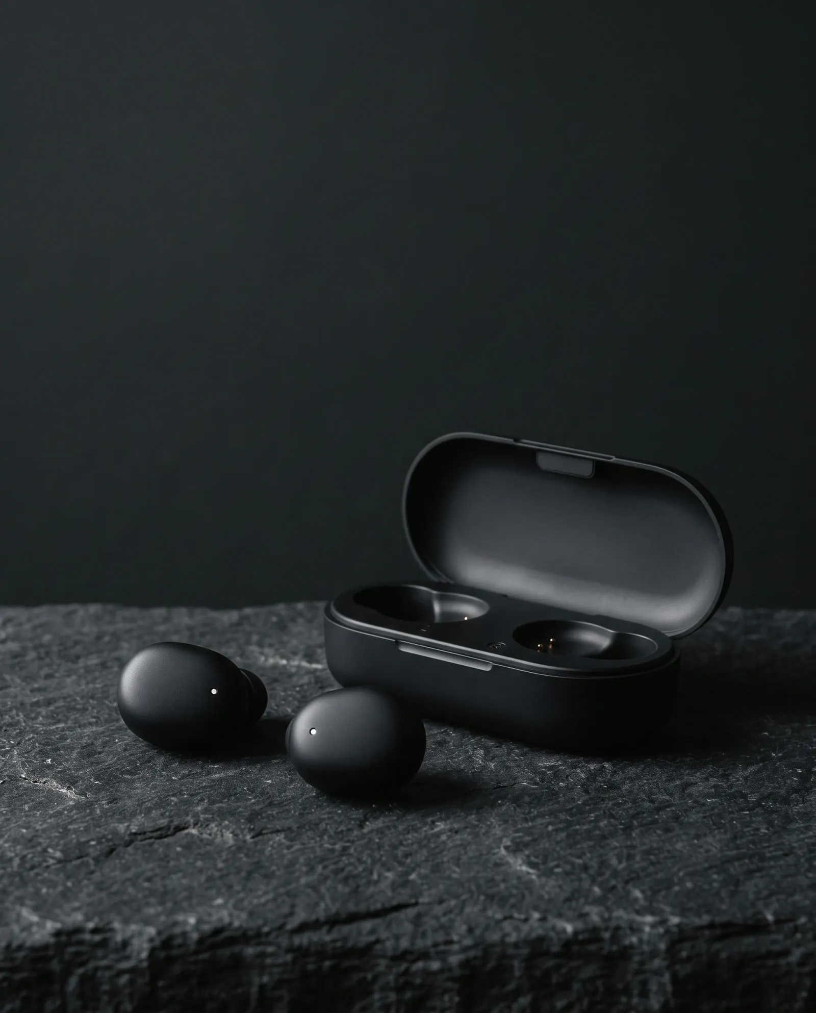 Hush earbuds next to their open charging case on dark stone